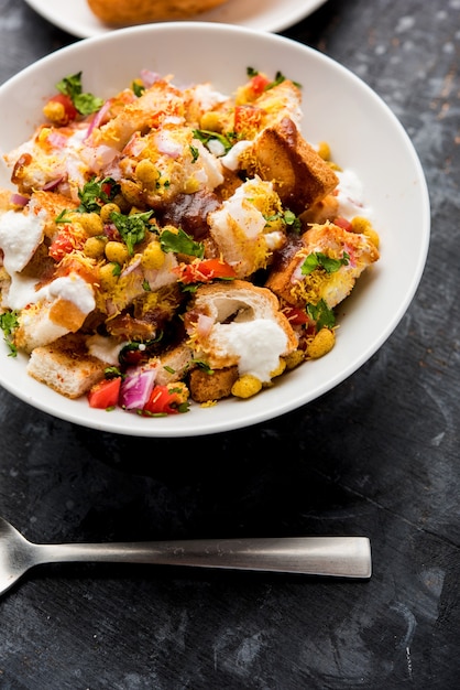 Bread chaat, chat is a yummy starter or appetizer from India, served in a bowl garnished with tomato, sev and coriander and masala. selective focus