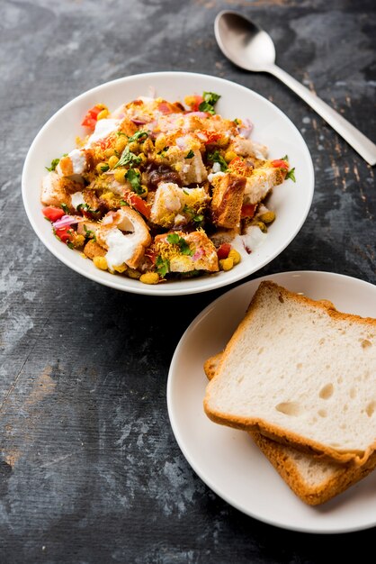 Bread chaat, chat is a yummy starter or appetizer from India, served in a bowl garnished with tomato, sev and coriander and masala. selective focus