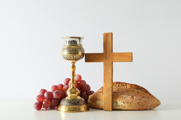 Bread cup grapes and wooden cross on white background
