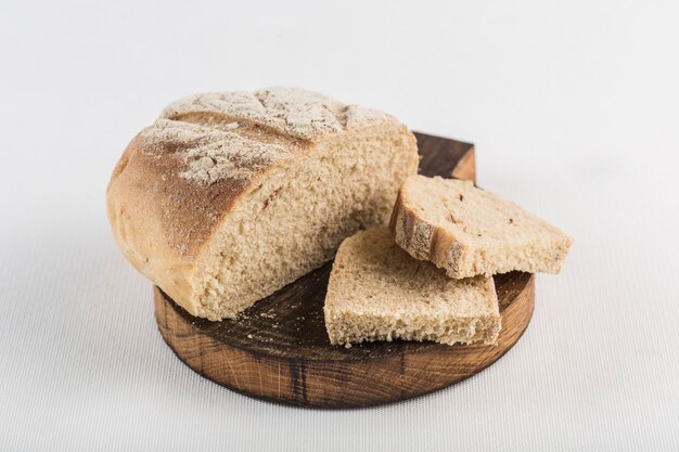 Bread cut into pieces lies on a wooden board on white