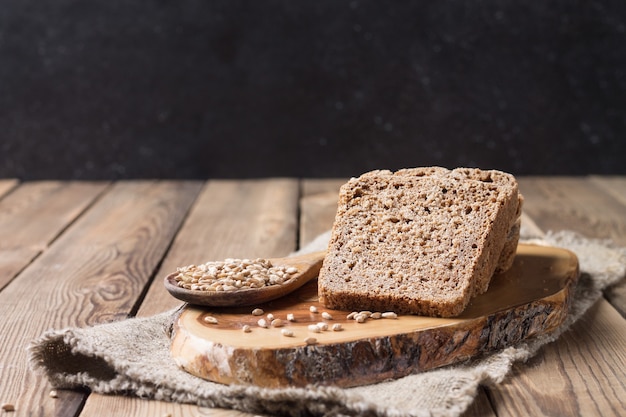 Foto il pane tagliato a pezzi, di farina di farro su lievito di farina, è adagiato sul tagliere della cucina, su un fondo di legno naturale