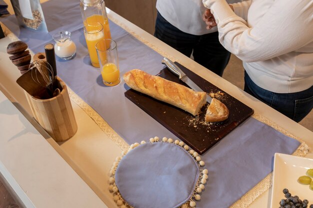 Bread cut on a kitchen counter accompanied by juice, milk and granola.