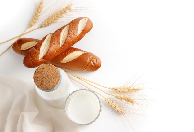 Bread and dairy products with ears of wheat top view