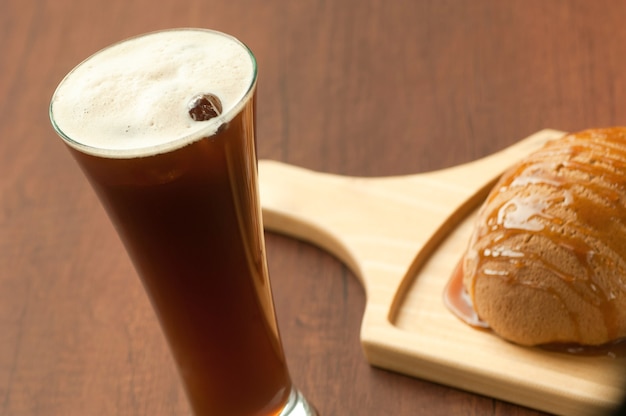 Bread drizzled with honey on a wooden plate and a glass of cocktail with berries