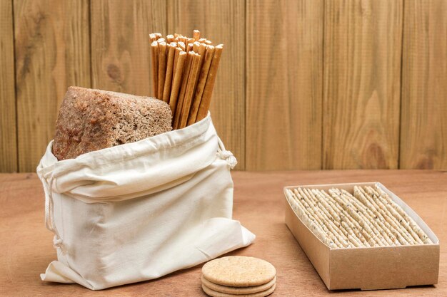 Bread and edible straw in linen bag Bread in cardboard box Ecological concept Wood background