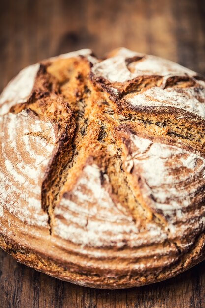 Bread.Fresh 둥근 바삭한 빵과 나무 테이블에 캐러웨이가 있습니다.