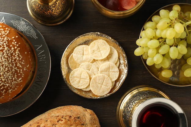 Bread grapes in bowls and cup of wine on wooden background top view