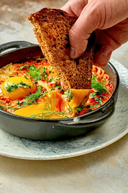 Bread is dipped in Shakshouka. Close-up, selective focus