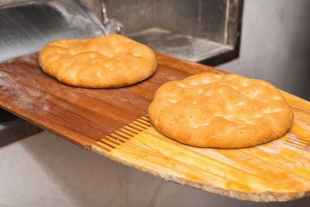 オーブンからパンを出してください。焼きたてのパン、ショベルで取り出したもの。