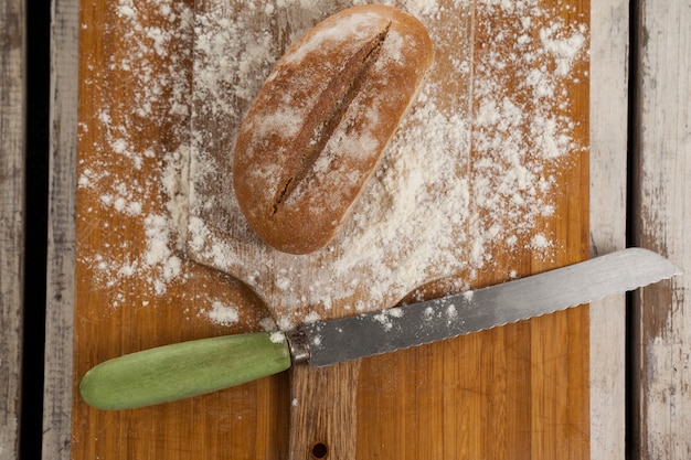 Bread loaf with knife on cutting board