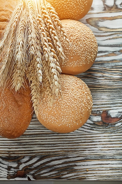 Bread long loaf ripe rye ears on wooden surface