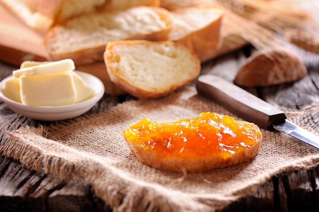 Bread and orange homemade jam on wooden table