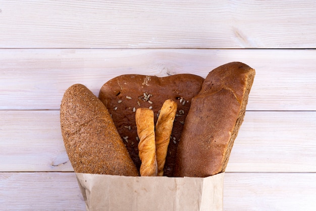 Bread in a paper bag on a light wooden