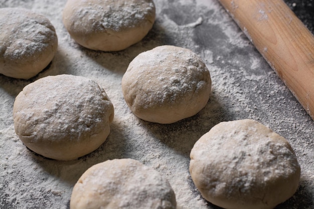 bread and raw flour with n rolling pin on black table