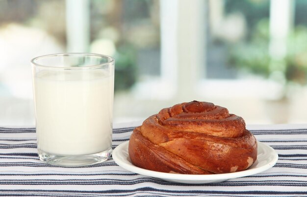 Bread roll and glass of milk on window background