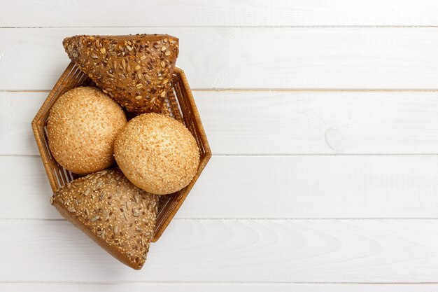 Bread rolls in the basket on rustic wooden background