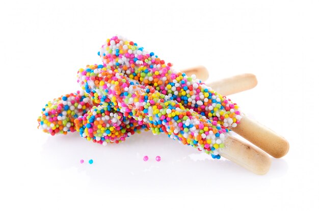 Bread stick with colorful sugar balls on white wall