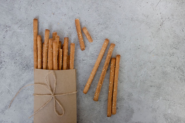 Bread sticks with sesame seeds and whole grain flour on grey background top view copy space