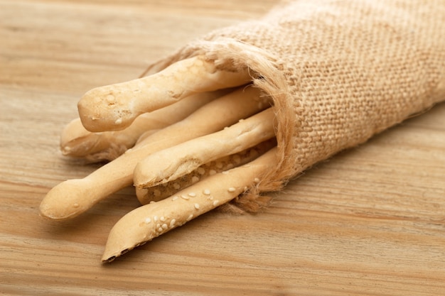 Bread sticks wrapped in burlap on a wooden background