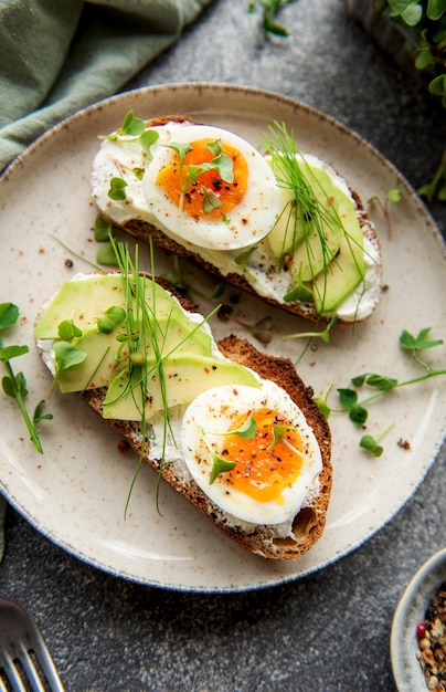 Bread toast boiled eggs avocado slice microgreens on a plate