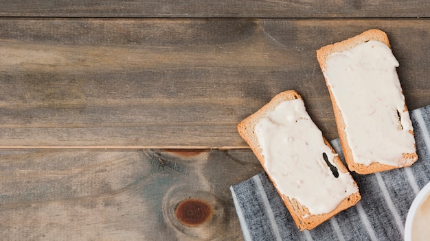 Bread toast with cheese spread on wooden table