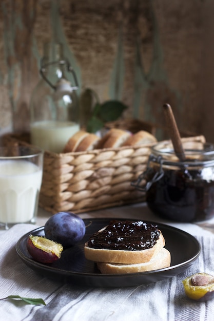 Bread toast with plum jam, served with milk and plums. rustic style.