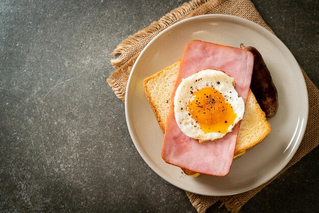 Bread toasted cheese topped ham and fried egg with pork sausage