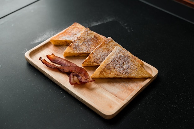 Bread toaster with bacon on wooden plate