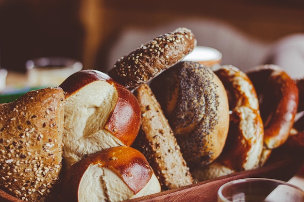 Bread variety on wooden basket. Traditional breakfast items on table. Vintage effect concept