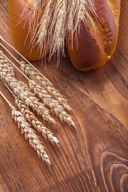 Bread and wheat ears on old wooden boards