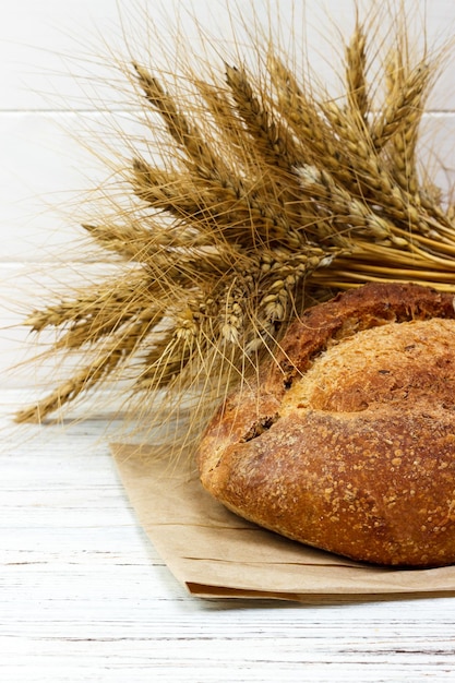 Bread and wheat on white wooden background