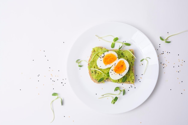 Pane con avocado verdure frutta e uova su sfondo bianco concetto di colazione sana