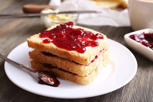 Bread with butter and homemade jam on wooden table closeup