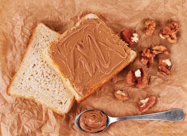 Photo bread with chocolate, walnuts and spoon on a paper background