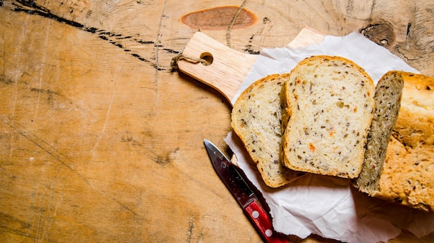 Bread with herbs and knife on Board. On a wooden table. Free space for text .