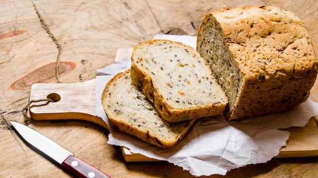 Bread with herbs and knife on Board. On a wooden table.