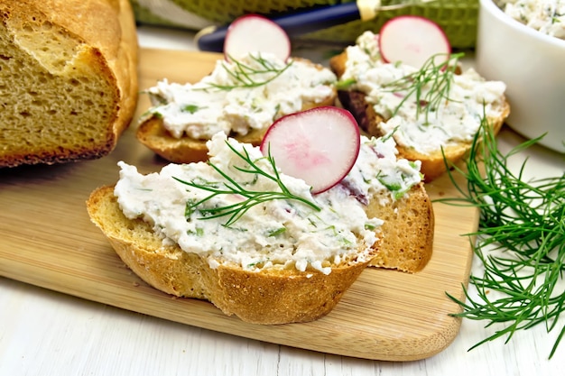 Pane con patè di ricotta aneto e ravanello su una tavola di legno un tovagliolo su sfondo tavolo in legno