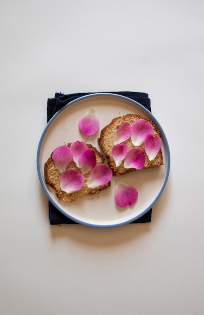 Bread with pink rose petals on a blue dish towel top flat lay