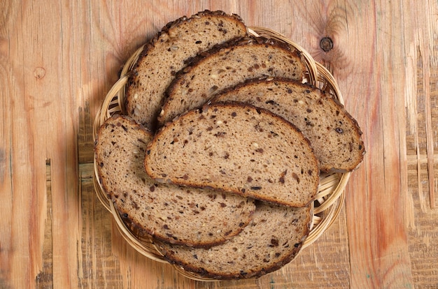 Bread with seeds, dried fruit and nuts slices on old wooden table