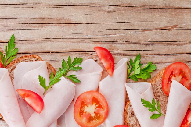 Foto pane con fette di prosciutto, pomodori freschi e prezzemolo