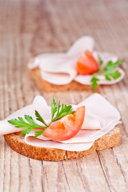 Bread with sliced ham, fresh tomatoes and parsley