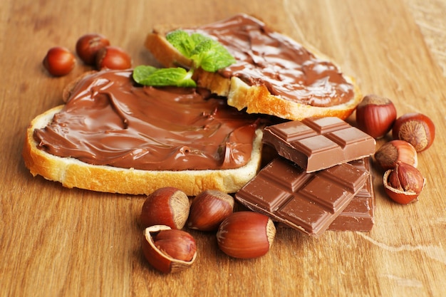 Bread with sweet chocolate hazelnut spread on wooden background