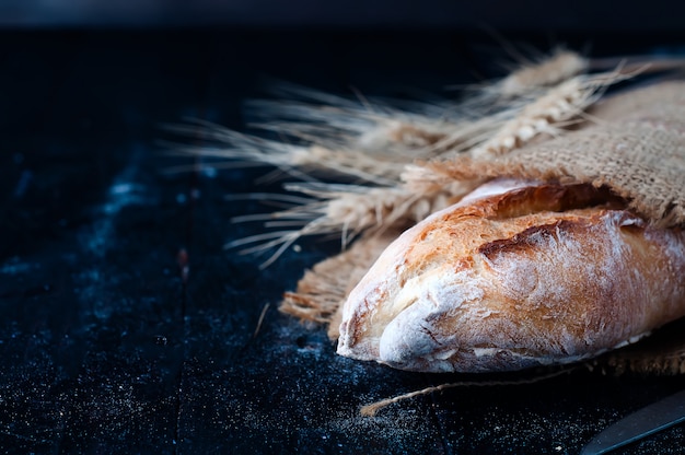 Photo bread with wheat ears on dark board