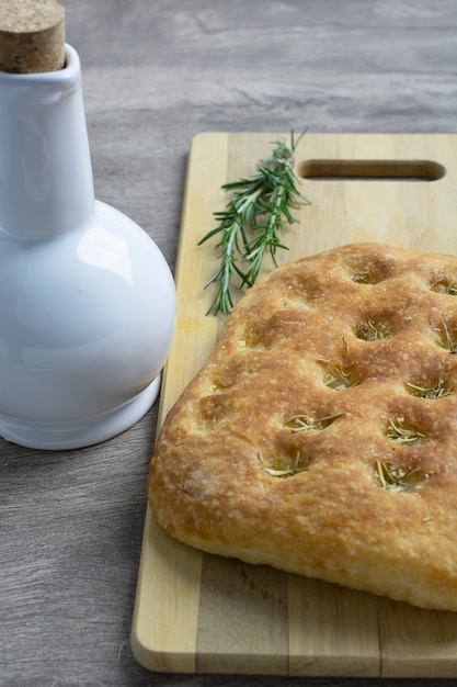 Bread over wood plate with rosemary and olive oil bottle