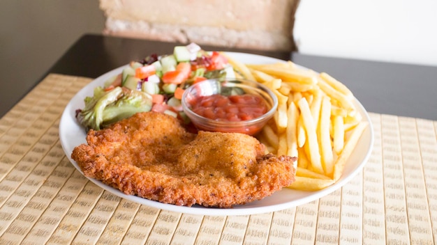 Breaded chicken breast with fries and rice.