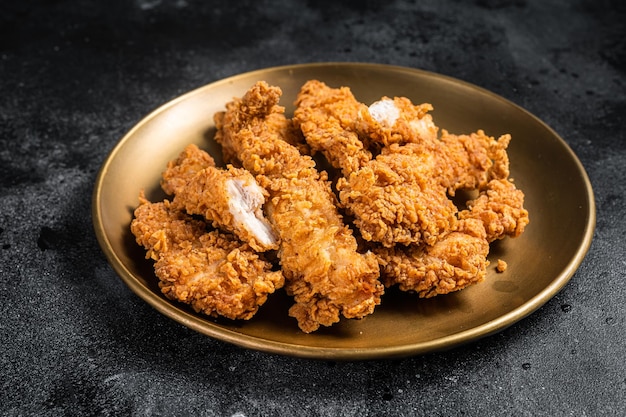 Photo breaded chicken strips breast fillet meat on a plate black backgrund top view