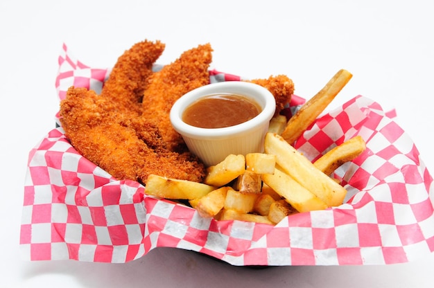 Breaded chicken strips with french fries and dipping sauce in a