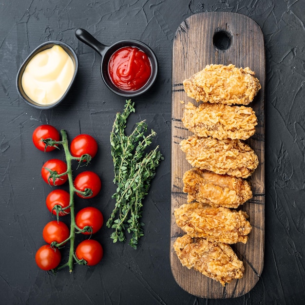 Breaded chicken wings on black background flat lay