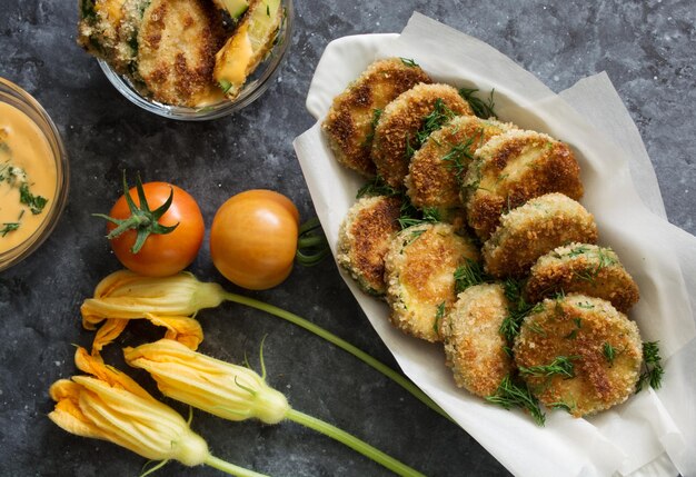 Breaded fried zucchini with tomatoes and sauce on dark background healthy lifestyle concept