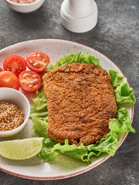 Breaded pork cutlet with cherry tomatoes mustard and lemon